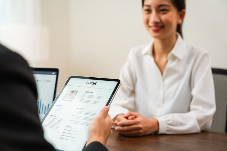 Proses wawancara kerja sebagai bagian dari strategi rekrutmen karyawan modern, dengan perekrut melihat resume digital di tablet.